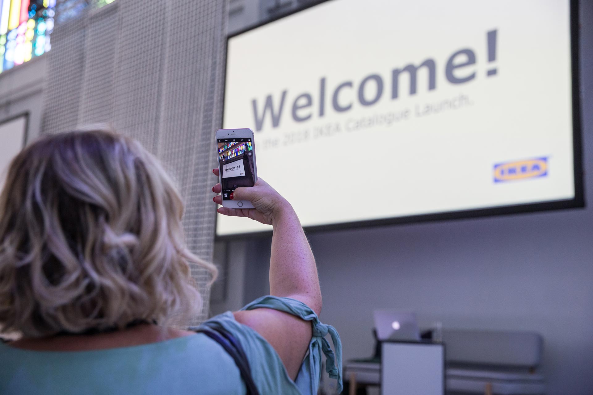 Frau fotografiert Eingang Catalogue Launch-Event in Baden mit Smartphone